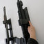 Person adjusting a mounted rifle against a white wall